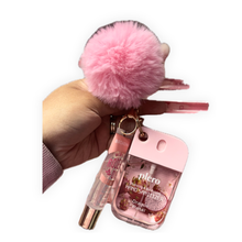 Load image into Gallery viewer, Boss Glam sanitizer keychain with lip gloss and hand sanitizer in pink with fluffy pom on soft blush background
